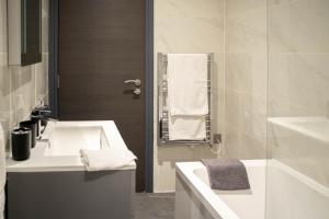 a white bathroom with a sink and a tub at Luxury Serviced Apartment With Super King Bed Workspace WiFi & Netflix Washer Dryer Close Parking in Bradford