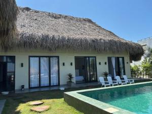 a villa with a thatched roof and a swimming pool at Cosamui Beach House in San Bernardo del Viento