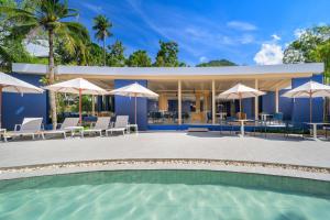 a pool with chairs and umbrellas in front of a house at Centara Karon Villas Phuket in Karon Beach