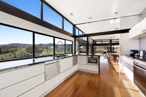 a kitchen with white cabinets and large windows at Riverdance At Conondale in Conondale