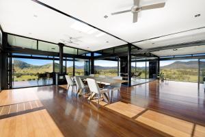 a dining room with a table and chairs and glass windows at Riverdance At Conondale in Conondale +16 photos