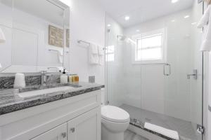 a white bathroom with a toilet and a glass shower at Siesta Key Beach Resort and Suites in Sarasota +97 photos