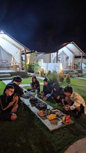 a group of people sitting around a table with food at The Breeze Glamping in Bangli +20 photos