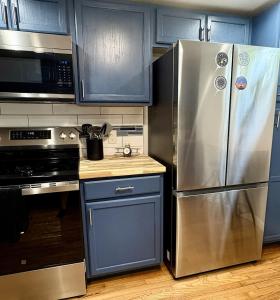 a kitchen with blue cabinets and a stainless steel refrigerator at The Sky Lounge-Brunswick in Brunswick