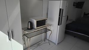 a microwave sitting on a table next to a refrigerator at Casa proximo ao aeroporto in Florianópolis