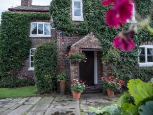 a brick house with flowers in front of it at Ash Farm Country House in Little Bollington