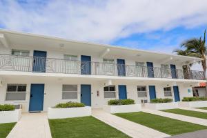 a large white building with blue doors and grass at Siesta Key Beach Resort and Suites in Sarasota