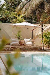 a pool with pillows and an umbrella next to a bed at Meraki in Polhena