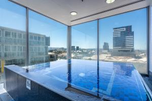 a large swimming pool in a building with large windows at Infinity on Morphett - Stay Central in the CBD in Adelaide
