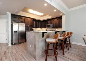 a kitchen with a counter with stools and a refrigerator at Phoenix Gulf Shores 903 in Gulf Shores