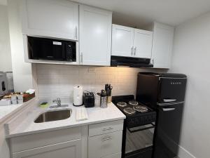 a kitchen with white cabinets and a black refrigerator at Renovated Beachfront Studio, New Kitchen, Pool in Daytona Beach