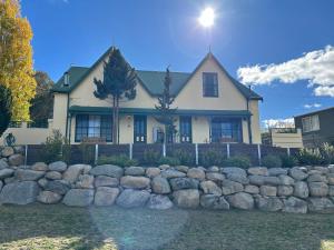 a house with a rock wall in front of it at Lakeside Chalet in Jindabyne