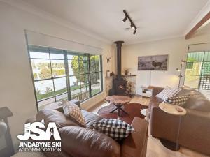 a living room with a leather couch and a fireplace at Lakeside Chalet in Jindabyne