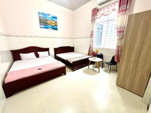a bedroom with a bed and a table and a window at Khách Sạn Homestay LaMera in Ben Tre