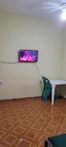 a tv on a wall with a table and a bench at Casa 2 quartos com ar condicionado e próximo ao centro in Cachoeiro de Itapemirim