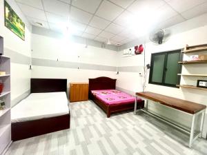 a small room with two beds and a desk at Khách Sạn Homestay LaMera in Ben Tre +7 photos