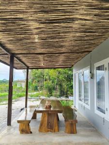 a picnic table under a wooden roof on a patio at Arkana Huis in Perawas