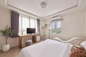 a white bedroom with a bed and a television at Quy Hung Hotel And Spa Central in Ho Chi Minh City
