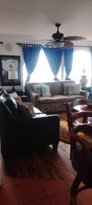 a living room with blue curtains and a couch at Summer Nights Oceanfront Villa - Pool & Jacuzzi in Primo Tapia