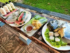 three plates of food on a wooden table at Leelavadee Villa Sea Views in Tha Sala