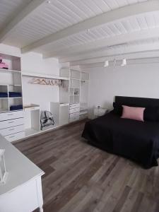 a white bedroom with a black bed and wooden floors at Chiche del mar in Playa Unión