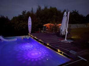 ein Swimmingpool bei Nacht mit Sonnenschirm und Terrasse in der Unterkunft Langaland Glamping unități de cazare în natură cu mic dejun și cină incluse in Susenii Bîrgăului