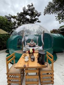a person sitting in a dome tent with a wooden table at Mindo GlamBird Glamping & Lodge in Mindo
