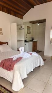 a bedroom with a large bed with white sheets at Estalagem Do Luar in Monte Verde