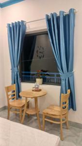 a table and chairs and a window with blue curtains at Homestay xóm nhỏ in Ninh Hải +17 photos