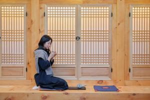 a woman sitting in a room looking at her cell phone at Hotel Jak Insadong by Anook in Seoul