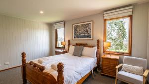 a bedroom with a bed and a chair and two windows at Camelot in Dinner Plain