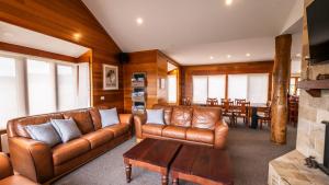 a living room with brown leather couches and a table at Camelot in Dinner Plain