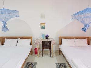 a room with two beds and a table with a chair at Wilpattu Lakwin Guest in Pahala Maragahawewa