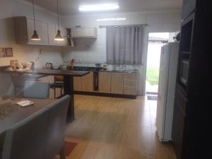 a kitchen with wooden floors and a kitchen with a refrigerator at Casa aconchegante e completa em Osório - Ótima localização in Osório