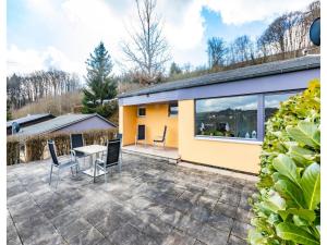 a patio with chairs and a table in front of a house at Bungalow im Campingpark in Waxweiler