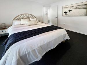 a bedroom with a large bed with white sheets at Oak Flats Escape in Oak Flats +16 photos