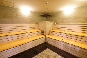a sauna with wooden benches and a brick wall at Matsuyama New Grand Hotel in Matsuyama