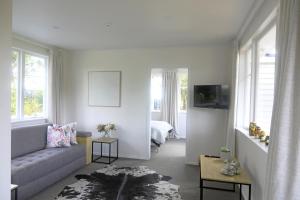 a living room with a couch and a bed at Glenmohr Cottage in Waipu