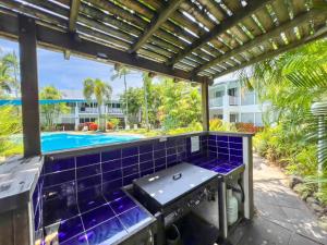 a patio with a grill and a swimming pool at Island Orchid in Airlie Beach