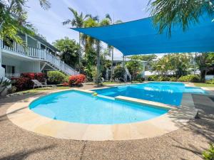 a large swimming pool with a blue umbrella over it at Island Orchid in Airlie Beach