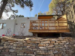 a house with a wooden deck and a stone wall at High Moon 4 Ten Thousand Waves Way in Santa Fe