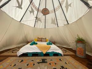 ein Schlafzimmer in einem Zelt mit einem Bett darin in der Unterkunft Langaland Glamping unități de cazare în natură cu mic dejun și cină incluse in Susenii Bîrgăului