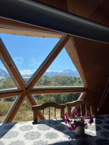 a room with a large window with a bench and flowers at Domo Kumelén Mahuida in Junín de los Andes +3 photos