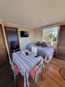 a bedroom with a bed and a table and chairs at Cabaña 2 a 4 personas in Carahuo
