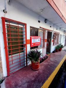 a building with red doors and potted plants on the sidewalk at Posada María Elvia Villahermosa in Villahermosa