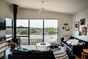 a living room with couches and a large window at Moonbird Beach Shack ~ Ocean Escape in Beaumaris Tasmania