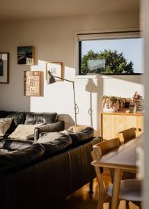 a living room with a black leather couch and a table at Moonbird Beach Shack ~ Ocean Escape in Beaumaris Tasmania