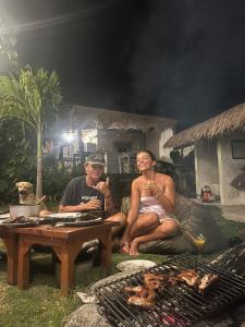 two men sitting around a table next to a grill at The Edge Lembongan in Nusa Lembongan