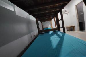 ein Zimmer mit einem blauen Bett in einem Zimmer mit Fenster in der Unterkunft Boracay Backpackers in Boracay