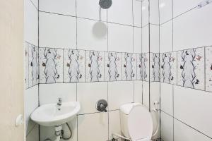 a white bathroom with a toilet and a sink at RedDoorz at Ingan Cio Homestay Berastagi in Berastagi